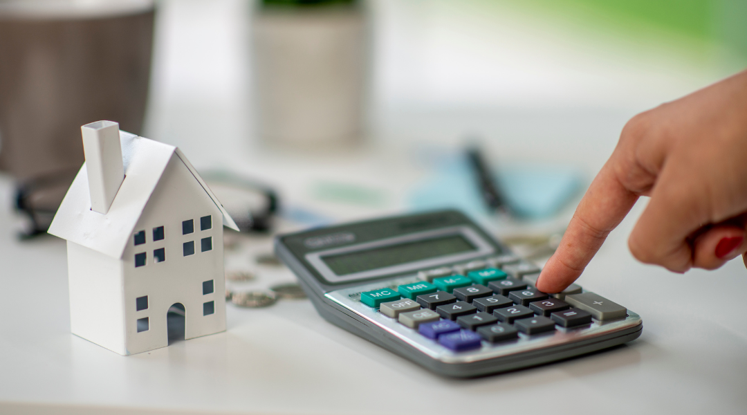 Finger on calculator with miniature home model