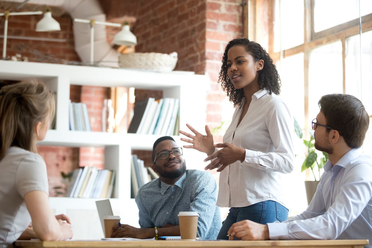 A female leader instructing her team in a corporate setting. 