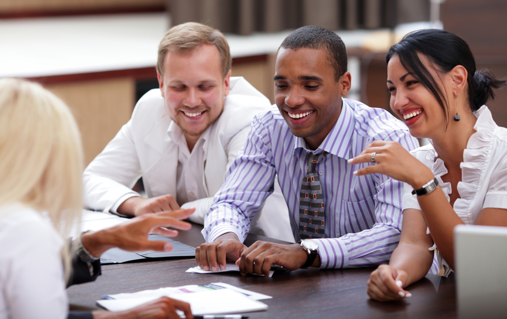 Three sales professionals at a job interview smiling.