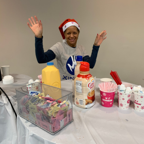 woman with santa hat on smiling next to table with treats on it