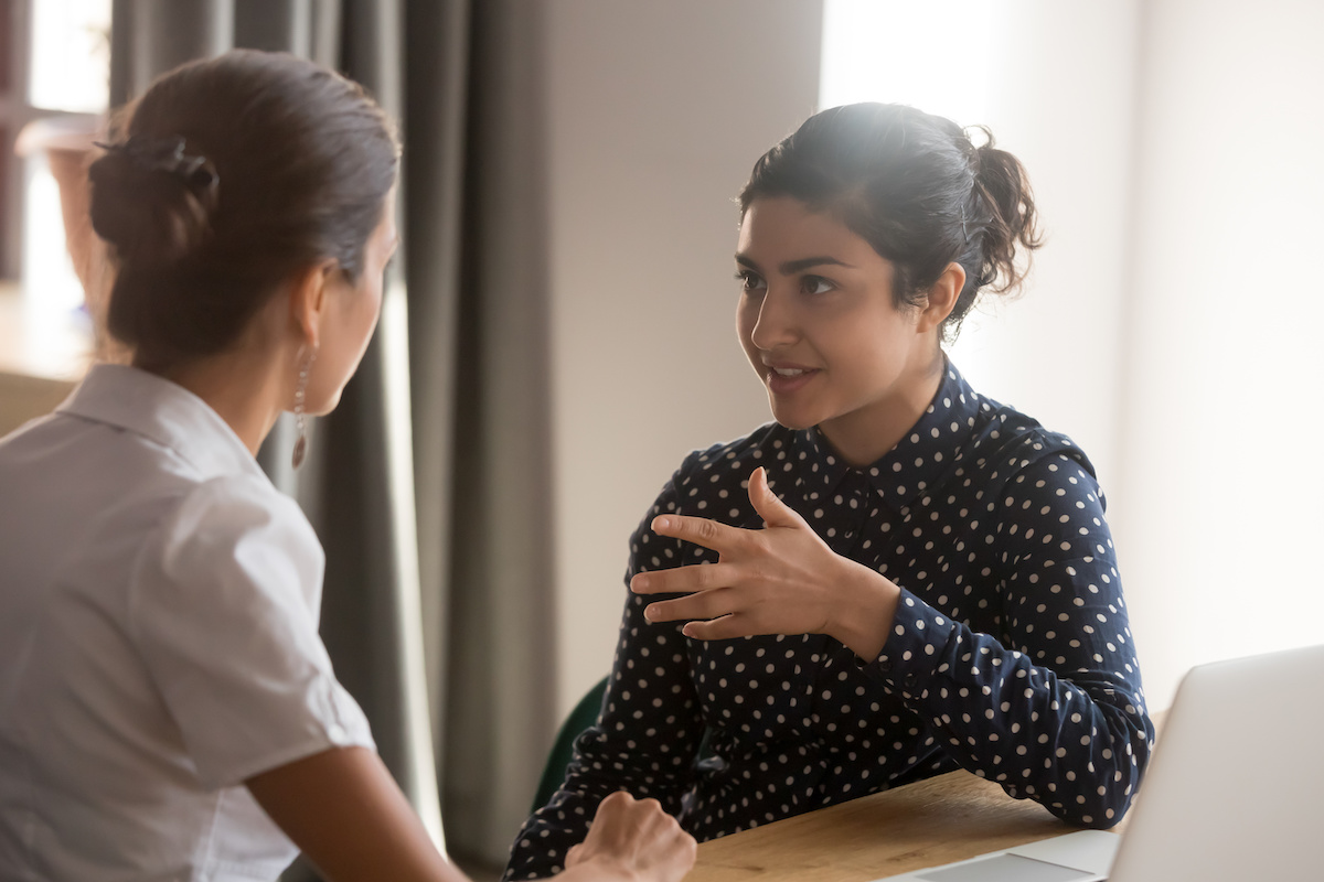 A female sales coach instructing a worker in a professional setting. 