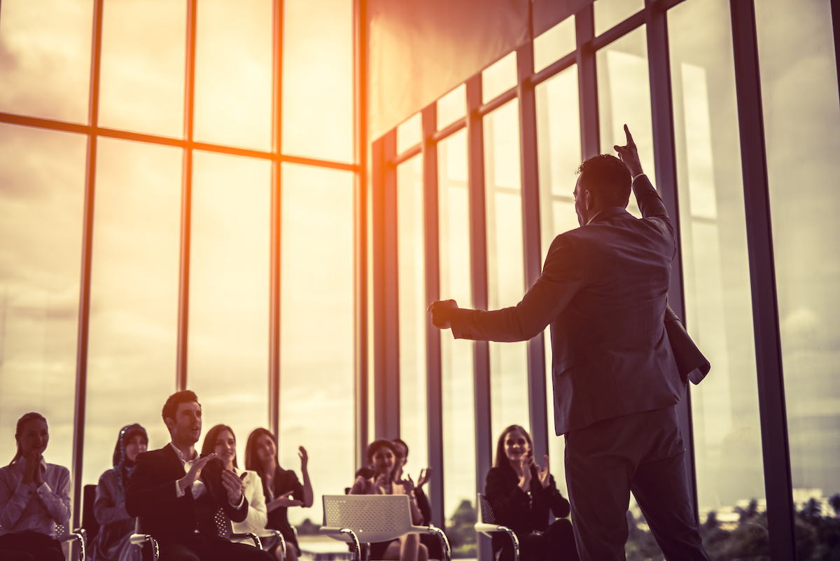 Leader speaking to a group of employees in an office setting.